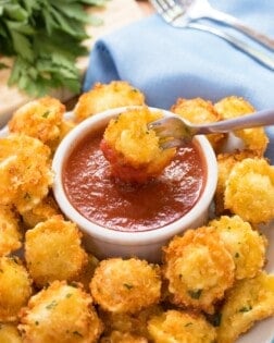 Parmesan Crusted Tortellini Bites with a fork dipping one into Marinara sauce.