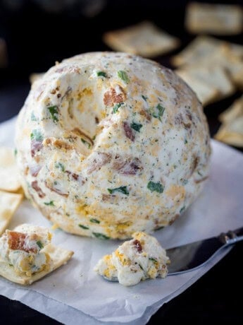A bacon ranch cheese ball on surrounded by crackers.