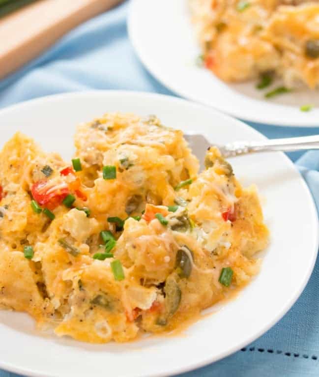 This crock pot egg scramble makes busy mornings easy! With little effort, you'll be eating light and fluffy eggs loaded with cheese and your favorite veggies! There is even an easy way to prep the night before so you can set it and forget it the next morning! A white bowl filled with soft scrambled eggs topped with diced chives.
