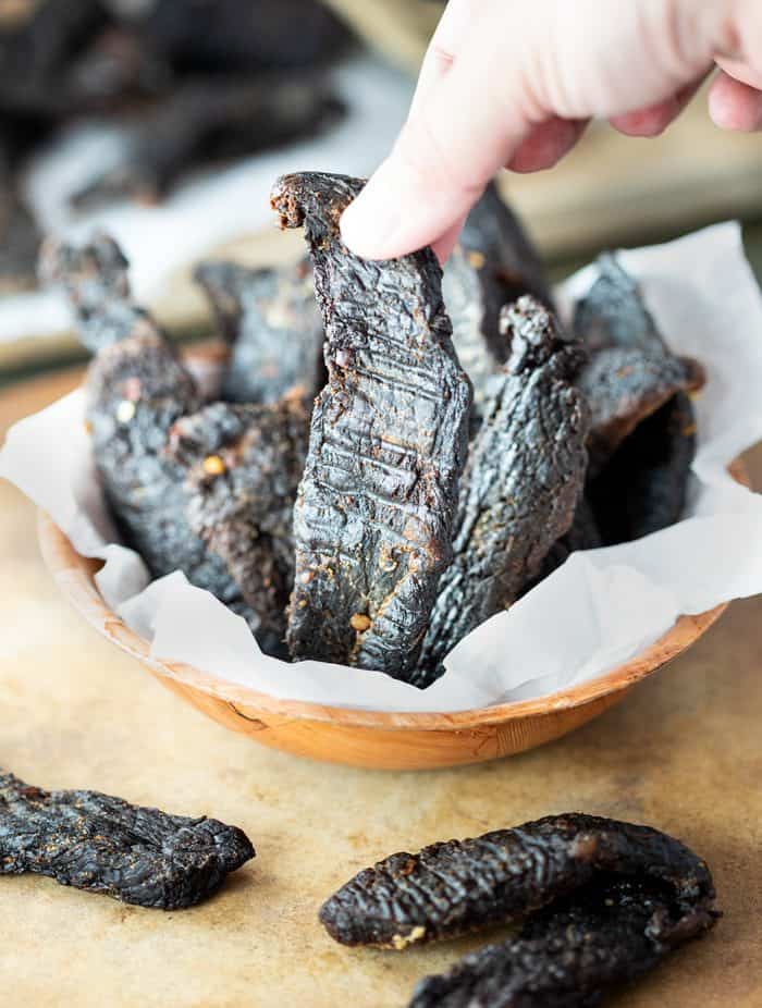 Thin slices of fresh meat are immersed in a flavorful marinade for several hours and then dehydrated or baked to create perfectly textured homemade beef jerky. Homemade-Beef-Jerky