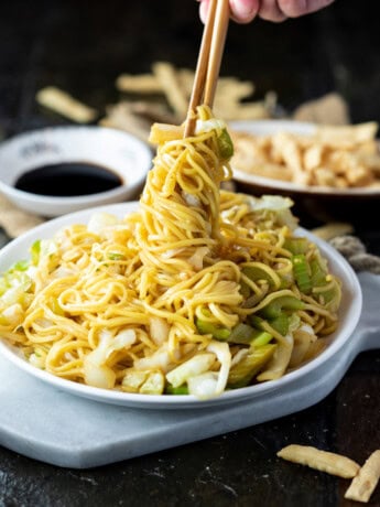 A white plate with Panda Express Chow Mein being twisted up with chopsticks.