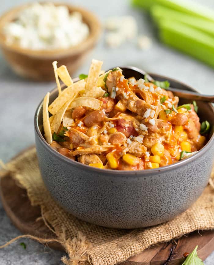 Grey bowl filled with buffalo chicken chili with crispy tortilla strips on top.