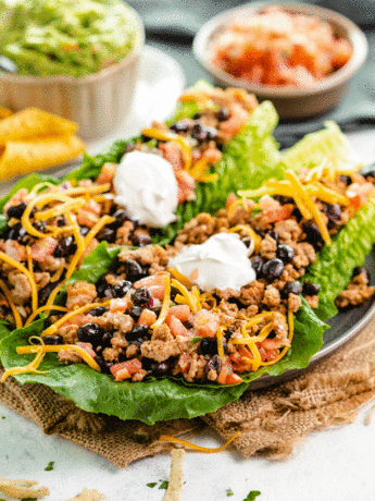 A plate with turkey taco lettuce wraps topped with sour cream.