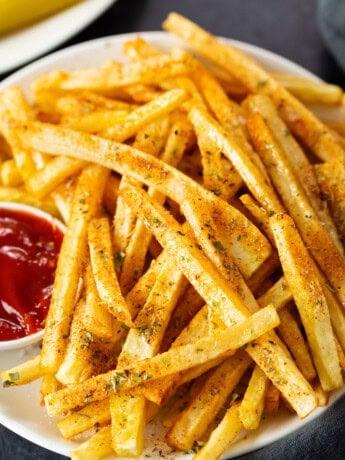 Seasoned french fries on a white plate.