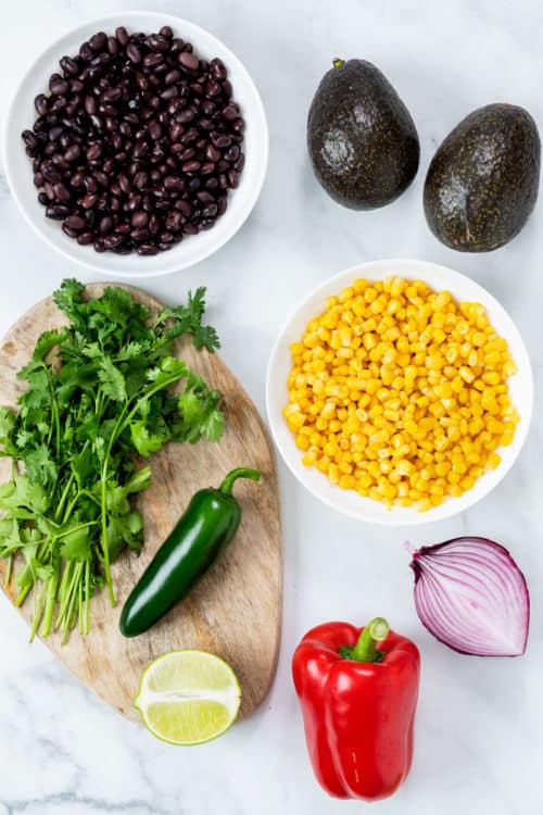 A white surface with ingredients for making cowboy caviar.