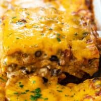A slice of Taco Lasagna being pulled up from a casserole dish.