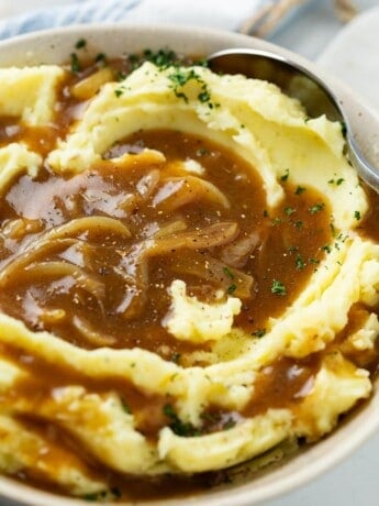 A bowl of creamy mashed potatoes topped with brown onion gravy.