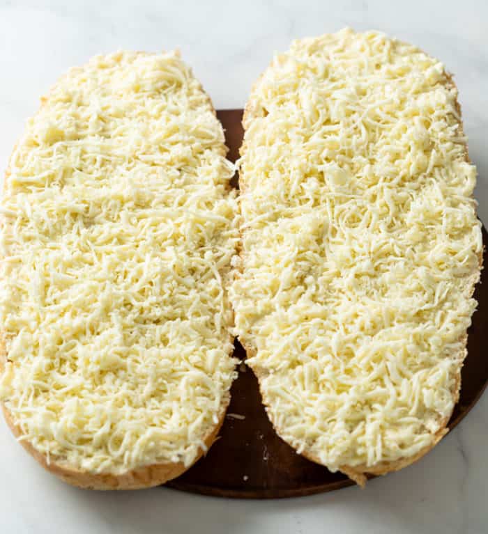 French bread with garlic butter, Parmesan, and mozzarella cheese on top before being baked to make Garlic Bread with Cheese.