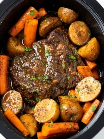 A Crock Pot Roast in a Crock with Potatoes, potatoes, and gravy.