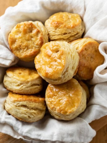 A bowl of buttermilk biscuits with a cloth underneath.
