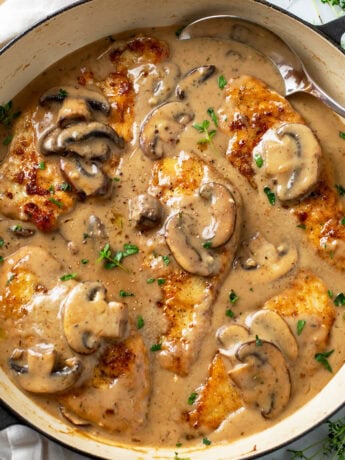 Mushroom Chicken in a skillet with sauce, mushrooms, and thyme.
