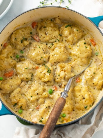 Chicken and Dumplings in a Dutch oven with a spoon on the side.