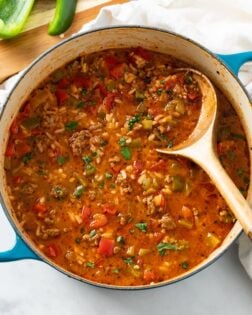 A soup pot filled with Stuffed Pepper Soup with a wooden spoon in it.