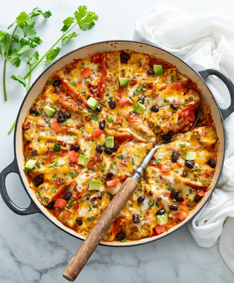 A baking dish filled with Taco Stuffed Shells with a spoon in it.