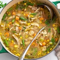 Chicken Vegetable Soup in a soup pot with a ladle and fresh parsley on top.