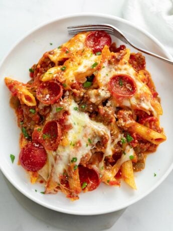 A white plate of Pizza Pasta with Pepperoni and meat sauce.