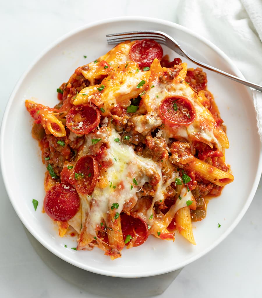 A white plate of Pizza Pasta with Pepperoni and meat sauce.
