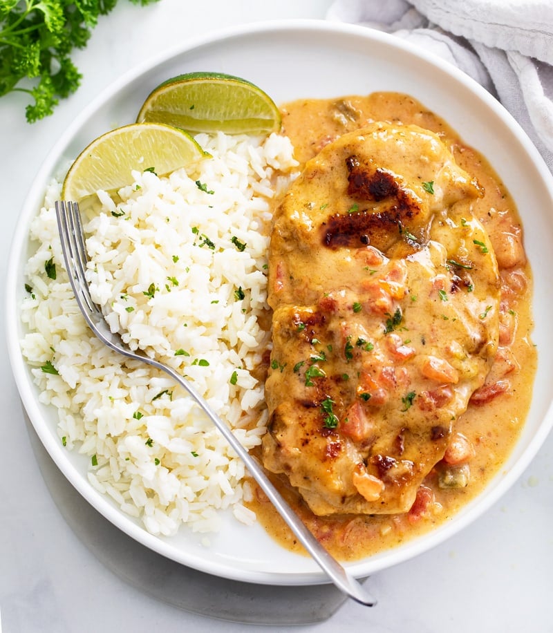 Cajun Chicken on a white plate with lime wedges and rice.