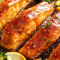Honey Glazed Salmon in a cast iron skillet with parsley, lemon wedges, and broccoli.