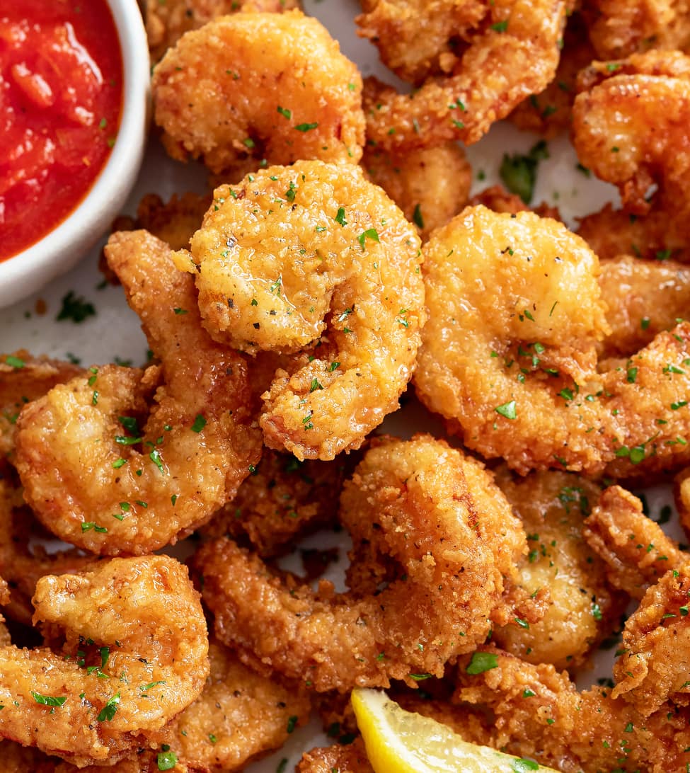 A pile of crispy fried shrimp with chopped parsley on top.