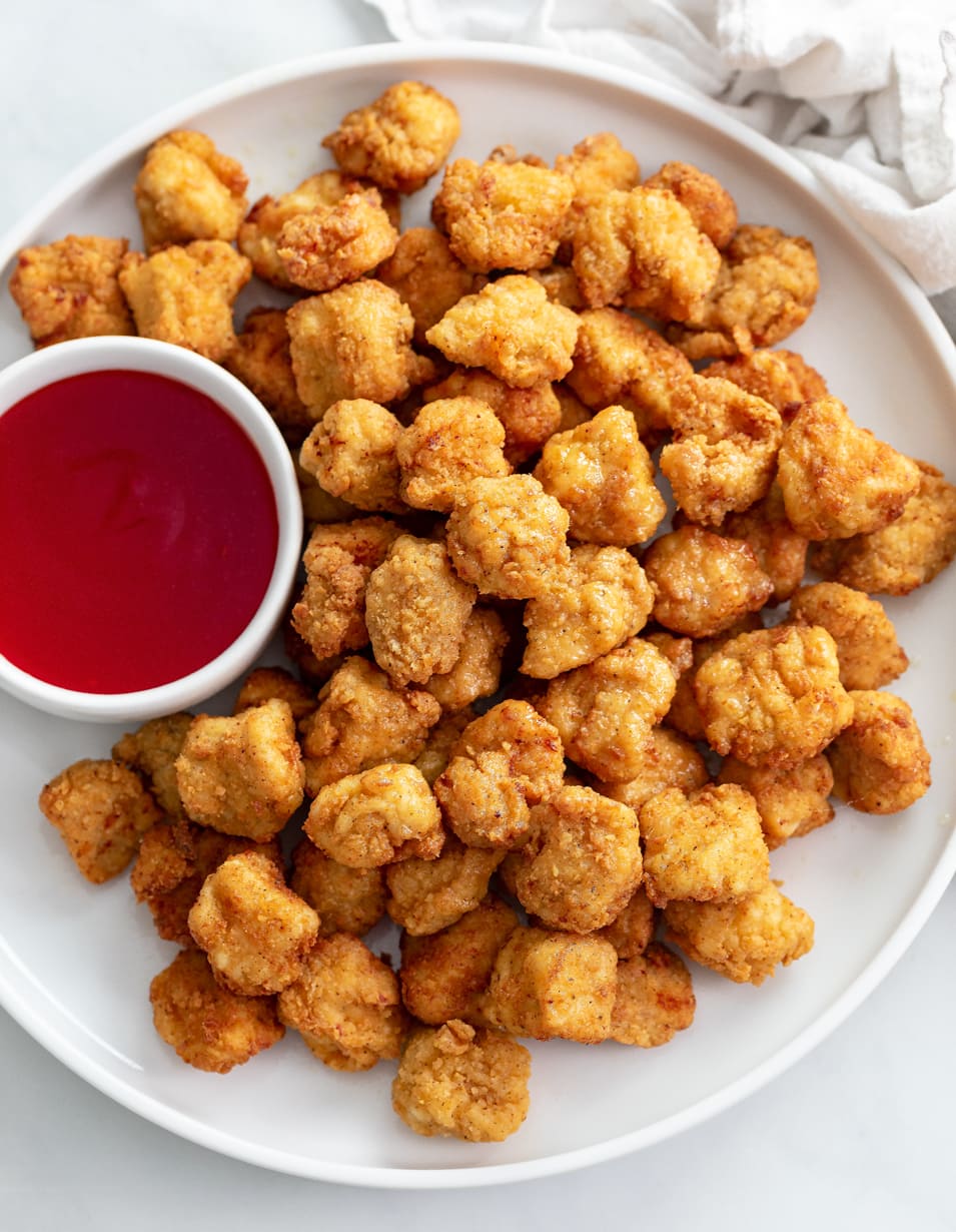 Popcorn Chicken on a white plate with sweet and sour sauce.