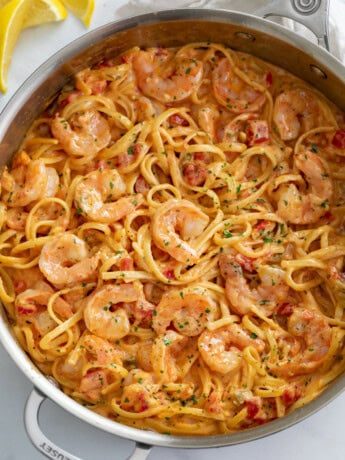 A skillet of shrimp pasta with linguine in a creamy sauce.