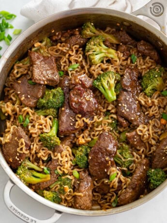 A skillet of Ramen Noodles with Beef and Broccoli in a brown sauce.