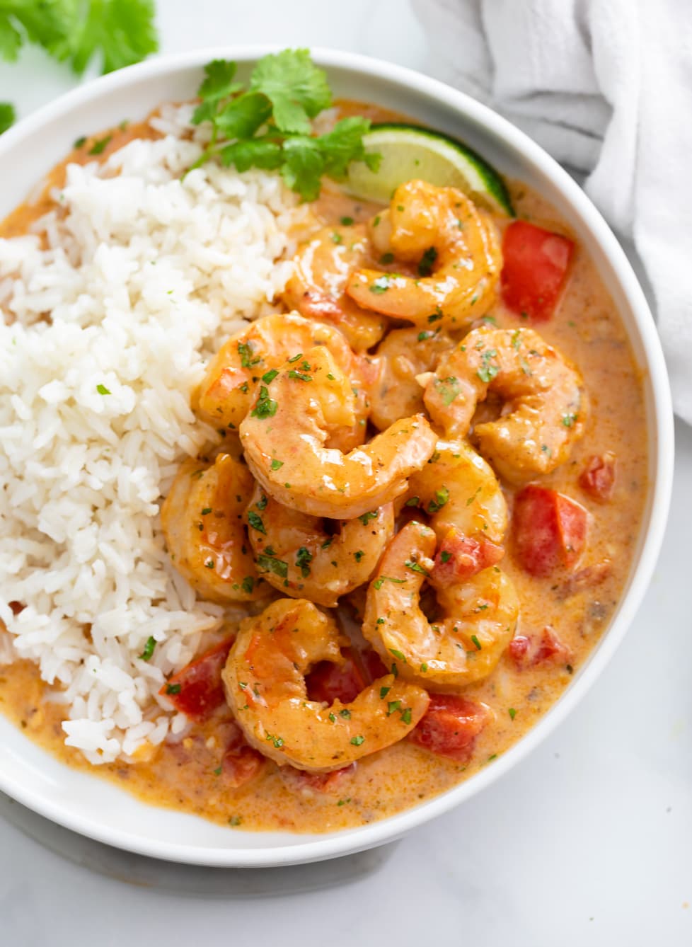 Cajun Shrimp on a white plate with sauce and white rice.