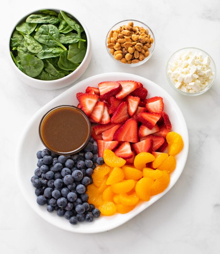 Spinach Salad Ingredients on a white plate and in bowls.