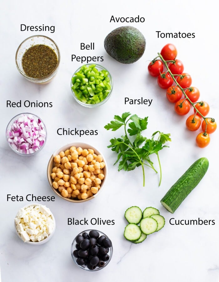 Ingredients for making Chickpea Salad on a white surface with labels.