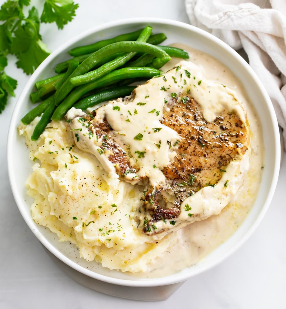 Ranch Pork Chops on a white plate with mashed potatoes and green beans.