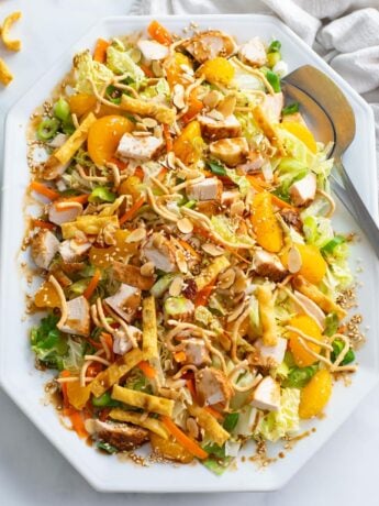 A white platter filled with Chinese Chicken Salad and homemade dressing.