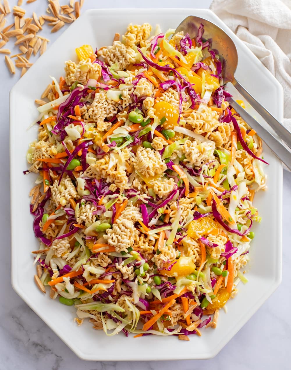 Ramen Noodle Salad on a white platter with serving spoons on the side.