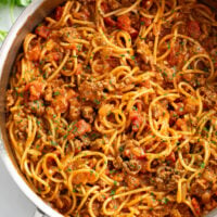 Taco Spaghetti in a skillet with taco meat and tomatoes.