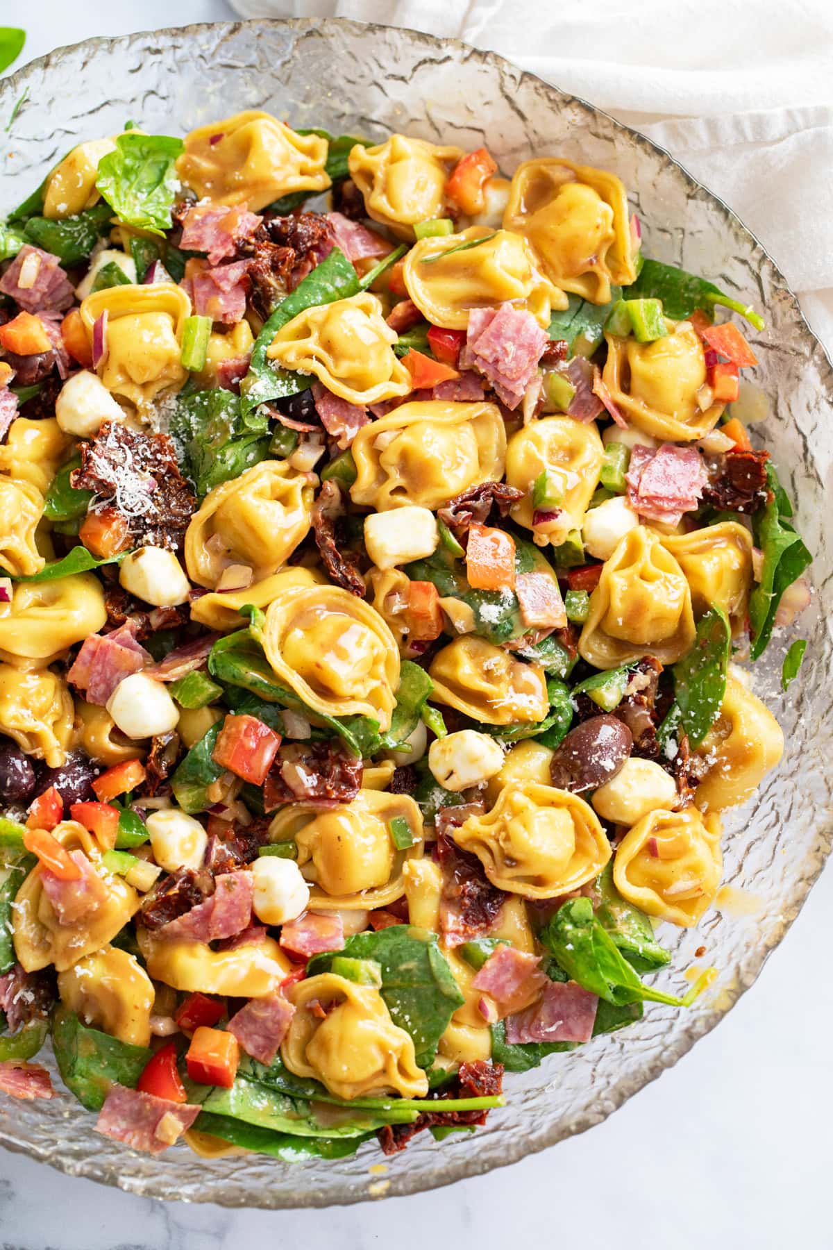 Tortellini Pasta Salad in meat, vegetables, and cheese in a glass bowl.