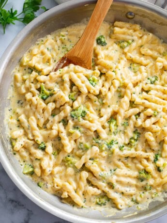 Cheese Pasta in a stainless steel skillet with a wooden spoon.