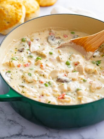 A Dutch oven filled with Chicken a la King with a wooden spoon in it.