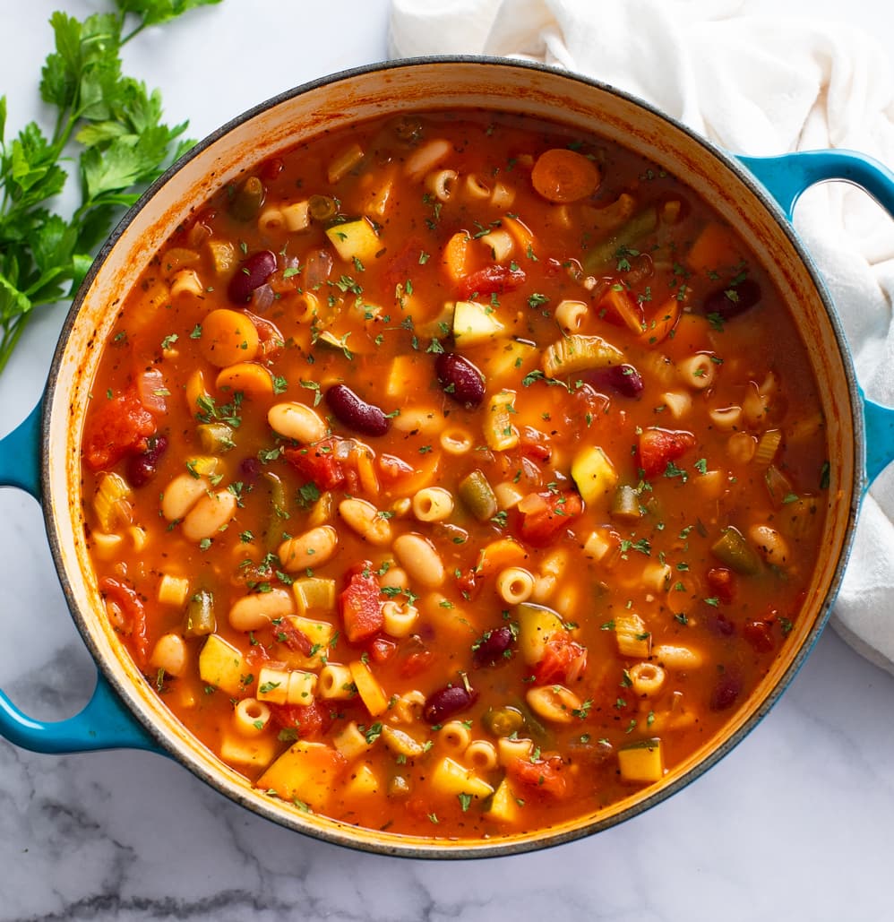 A soup pot of Minestrone Soup with fresh parsley on the side.