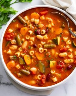 Minestrone Soup in a white bowl with a spoon on the side.