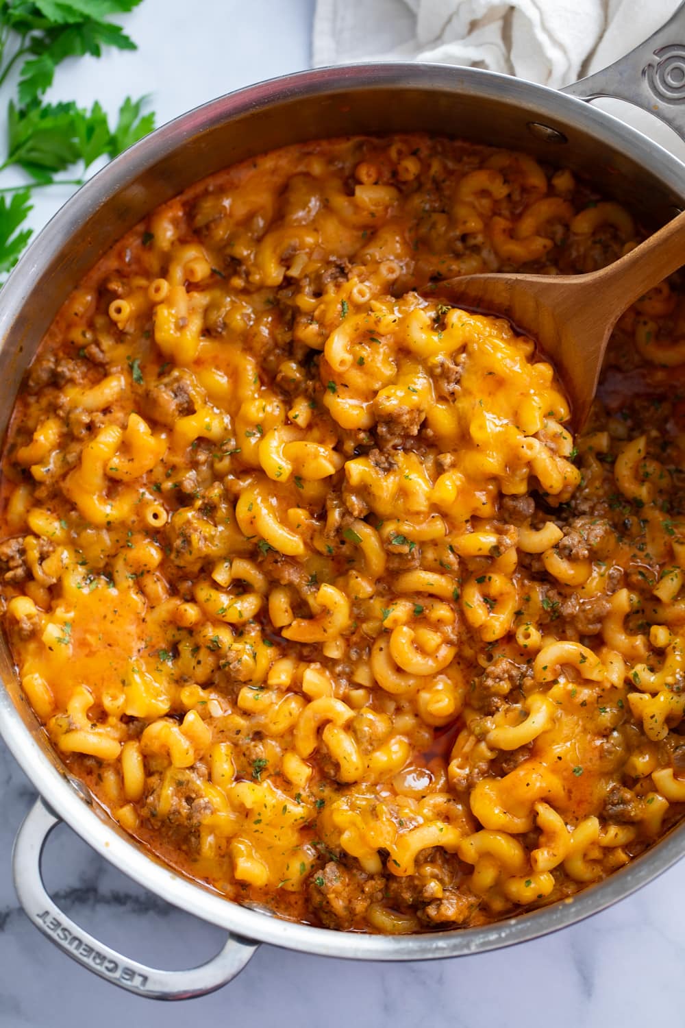 A skillet of Beefaroni with a wooden spoon in it.