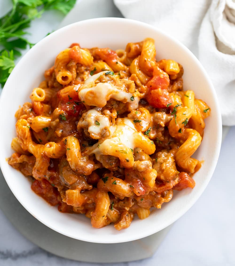 Italian Sausage Pasta on a white plate with cheese on top.