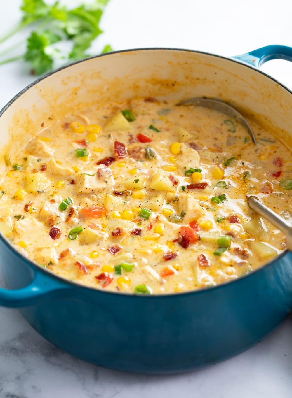 Chicken Corn Chowder in a blue soup pot with a ladle on the side.