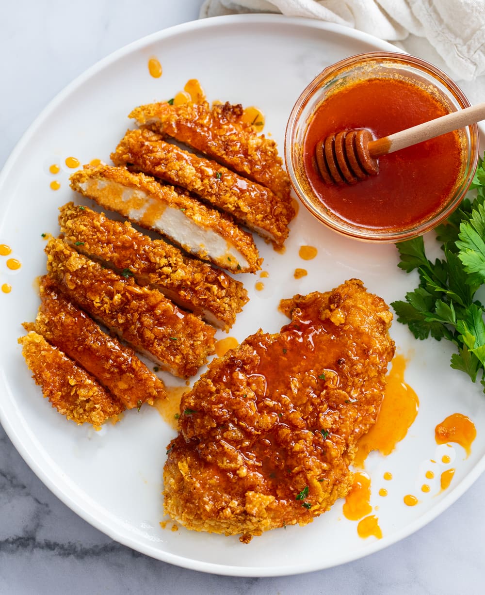 Hot Honey Chicken on a white plate with hot honey dipping sauce.