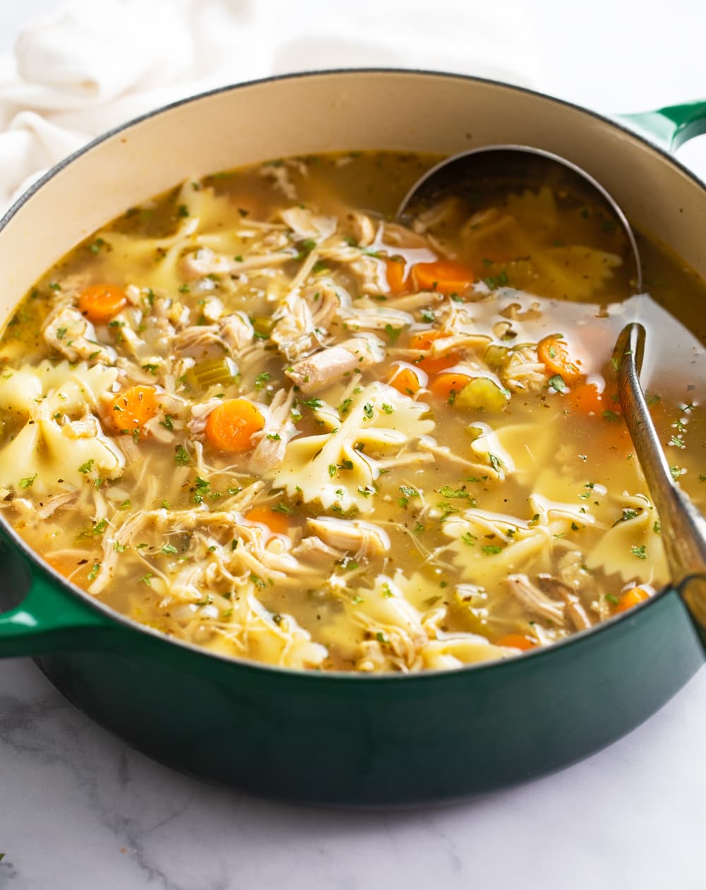 Turkey Soup in a green soup pot with a ladle on the side.