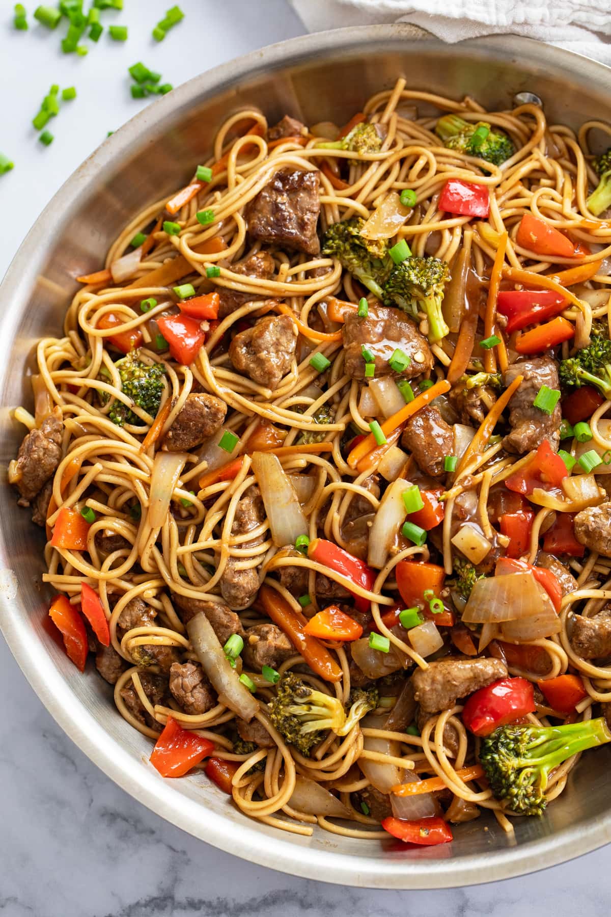 Beef Lo Mein in a skillet with brown sauce and vegetables.