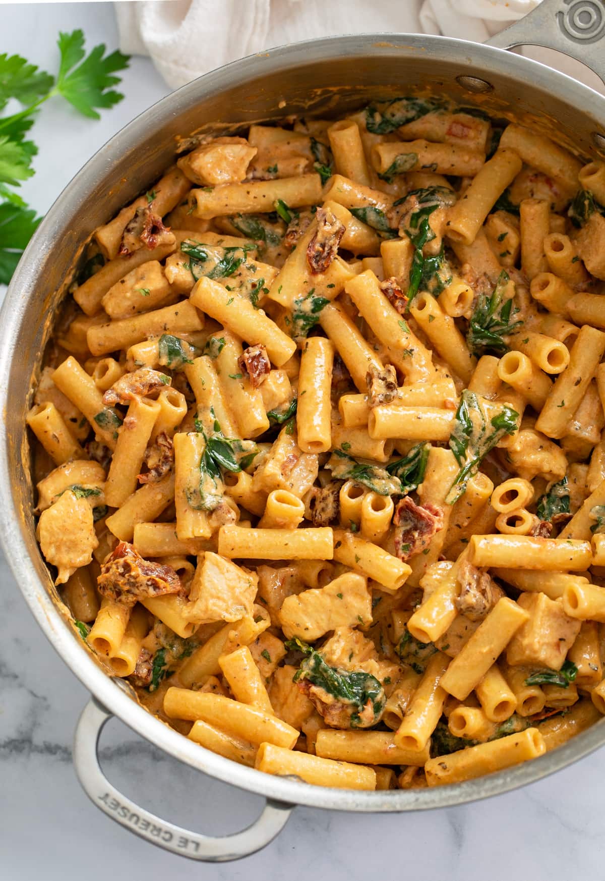 Marry Me Chicken in a skillet with a tomato cream sauce, sun-dried tomatoes, and spinach.