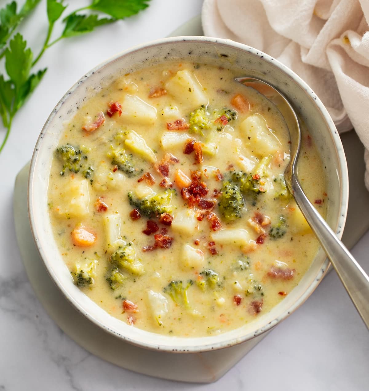 Broccoli and Potato Soup in a soup bowl with bacon on top and a spoon on the side.