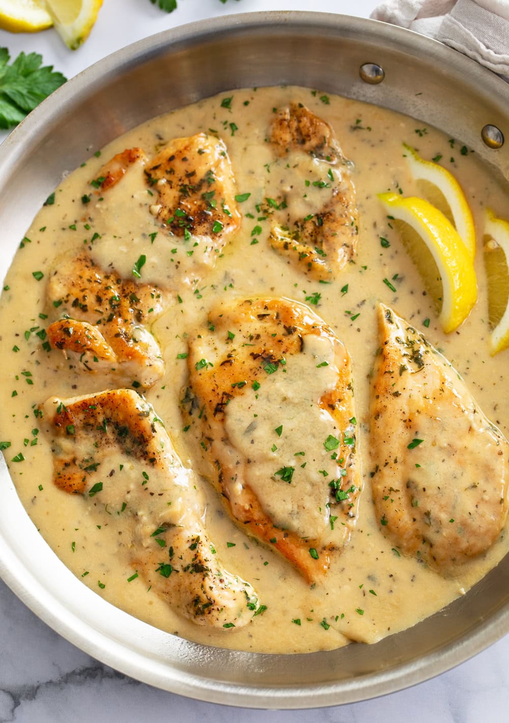 Garlic Parmesan Chicken in a skillet with sauce and fresh parsley on top.