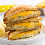 A stack of Tuna Melts with grilled bread and melted cheese on a white plate.