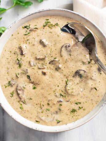 A bowl of Cream of Mushroom Soup with a spoon on the side.